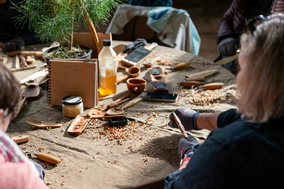 People carving wood at a workshop table