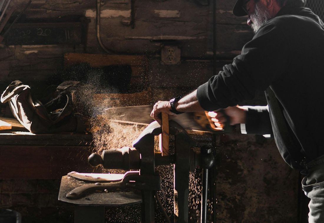 A craftsman working wood at a bench in a dim workshop